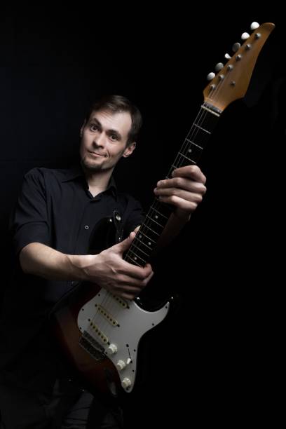 istock Guitarist playing raised the guitar vertically look at camera on black background 1483895879