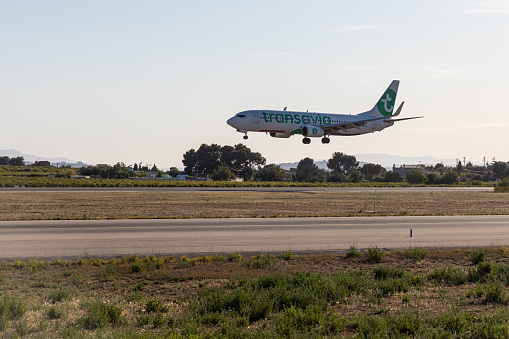 Valencia, Spain - 04 04 2023: A White and green plane with chassis is landing on the landscape background