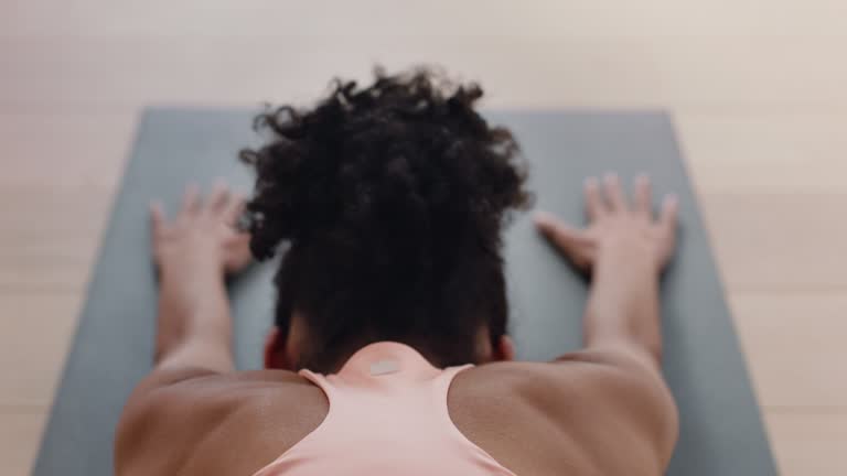 close up yoga class african american woman practicing childs pose enjoying healthy lifestyle exercising flexible body in fitness studio rear view