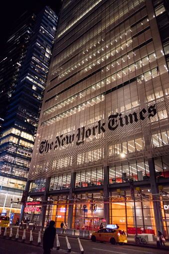 New York City, 8th Ave., - USA: The New York Times Building with large lettering illuminated at night with activity on street