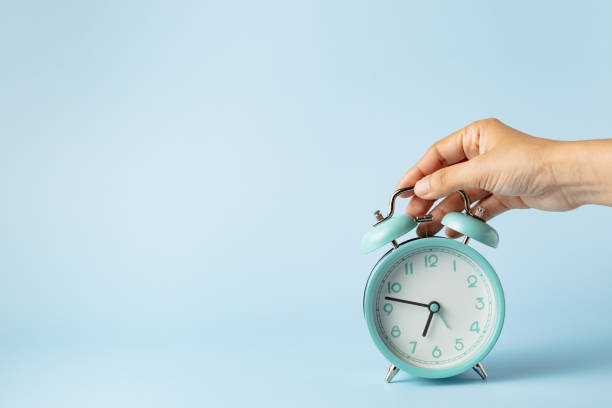 istock The bell alarm clock is turned off by hand against blue background 1483910264