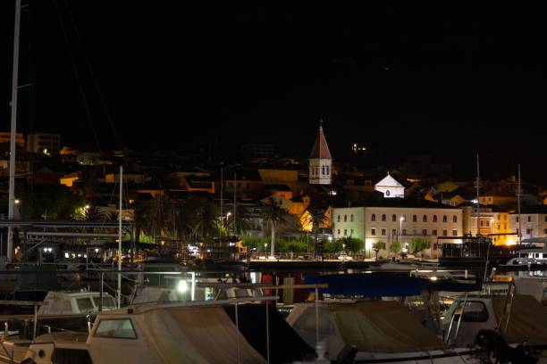 живописный вид на шумную гавань ночью, освещенную тусклым оранжевым светом в макарске, хорватия - harborage стоковые фото и изображения