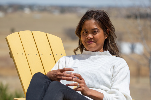 Beautiful female relaxing on a patio chair holding a drink.