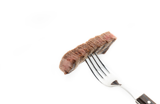 Slice of beef steak on meat fork isolated on white background.