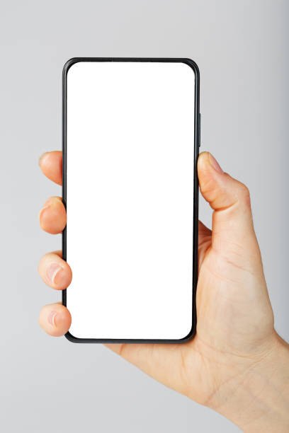 istock Hand holds black smartphone with blank white screen and modern frameless design isolated on gray background. 1483919972