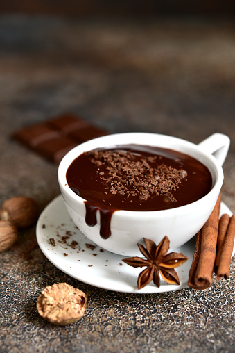 Hot chocolate with winter spices on a dark slate, stone or concrete background.