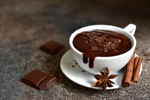 Hot chocolate with winter spices on a dark slate, stone or concrete background.