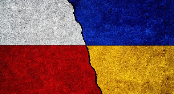 Ukraine and Poland flag on a wall with a crack. Ukraine and Poland relations