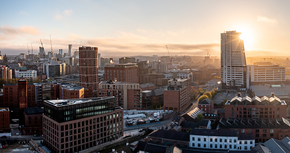 An aerial panoramic view of a Leeds cityscape skyline with modern architecture and  skyscrapers bathed in early morning sunlight at sunrise