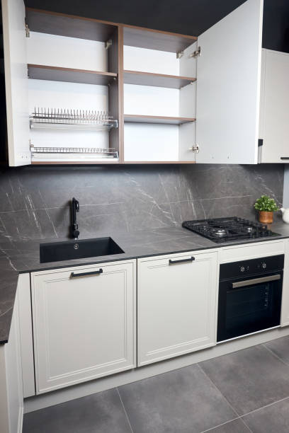 istock Interior of white and grey kitchen, horizontal linear layout. Luxury modern fitted flat design kitchen with opened cupboard shelves sideboard with dish drying cabinet vertical shot. 1483923873