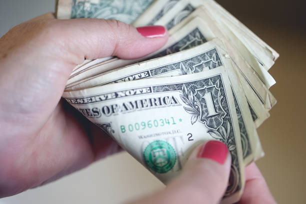 istock A woman holding and counting US one dollar bills. 1483924961