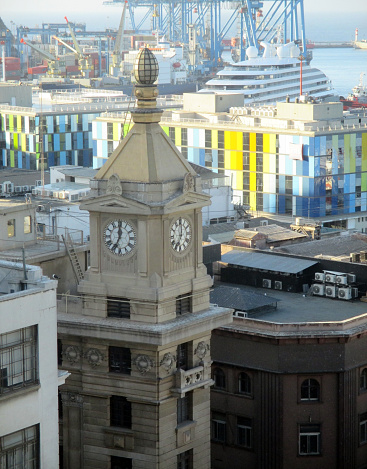 Torre Turri Valparaíso clock, in the foreground, behind a partial view of the port of Valparaíso at sunset on March 18, 2023.\nDeclared a UNESCO World Heritage Site.\nView from Paseo Gervasoni.