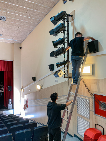 Two sound technicians working on the installation of lights and spotlights in a theater