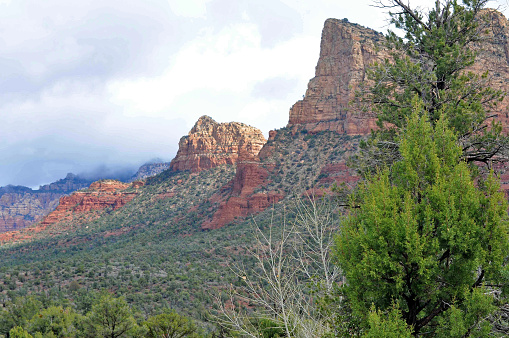 A desert town, Sedona, is surrounded by red-rock buttes, steep canyon walls and pine forest.