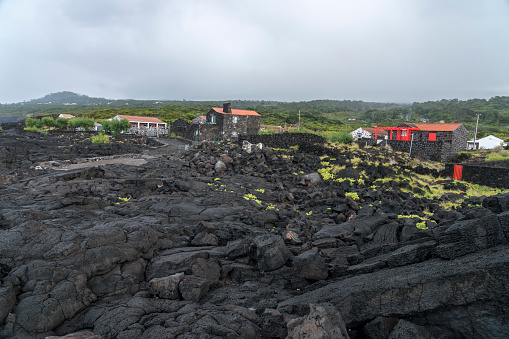 Small picturesque village, houses made of volcanic rocks, at the edge of black lava coast. Cabrito, Pico island, Azores