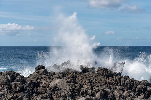 Foamy waves crash against the volcanic rocks, Pico island, Azores.