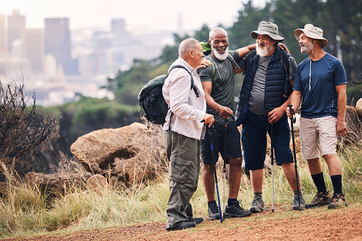 Hiking, support and hug with old men on mountain for fitness, trekking and adventure with city mockup. Motivation, discovery and expedition with friends on trail for health, retirement and journey