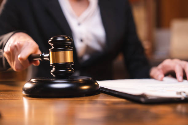 Judge gavel on the table with blurry books in the background stock photo