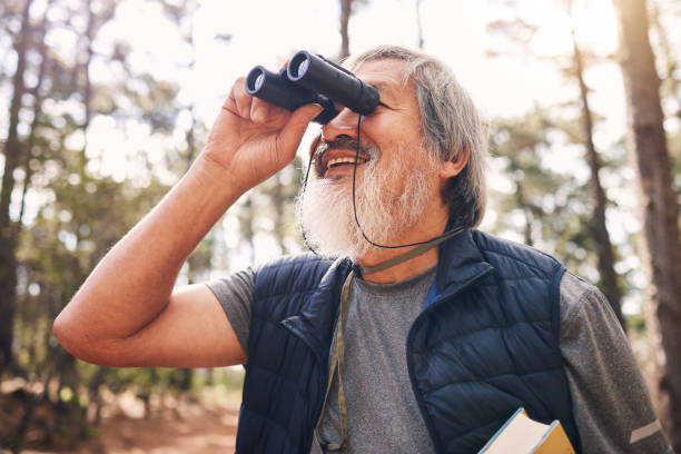 istock Binoculars, hiking and senior man in nature looking at view, sightseeing or watching. Binocular, adventure search and happy elderly male with field glasses, trekking or exploring on vacation outdoors 1483934861