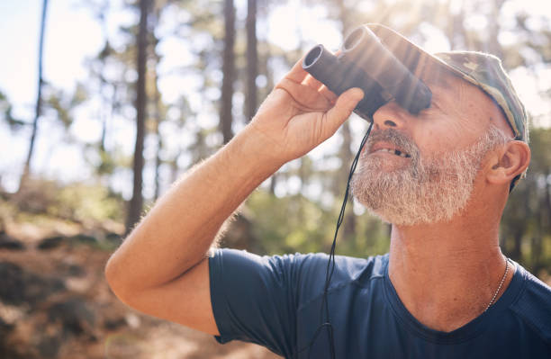 istock Binoculars, senior man and hiking in nature looking at view, sightseeing or watching. Binocular face, adventure search and elderly male with field glasses, trekking or exploring on vacation outdoors. 1483934863