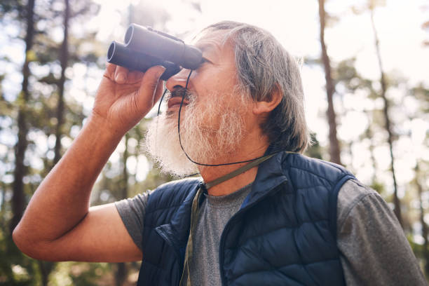 istock Hiking, binoculars and senior man in nature looking at view, sightseeing or watching. Binocular, adventure and elderly male with field glasses, trekking or exploring on holiday or vacation outdoors. 1483935891