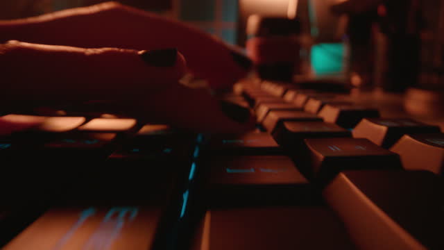 macro hands typing on keyboard computer programmer coding software using keyboard with blue backlight anonymous person hacking at night