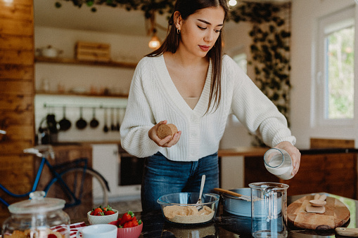 Young woman preparing cheesecake at home