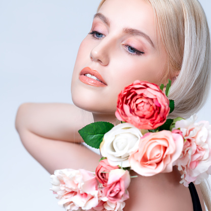 Closeup young personable woman with natural makeup and healthy soft skin holding rose for beauty care advertising in isolated background. Beautiful pretty model girl with flower concept.