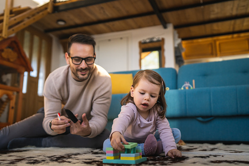 Father and daughter on the floor at home mature adult caucasian man play with finger puppets with his two years old child toddler girl having fun parenting and bonding family time concept copy space