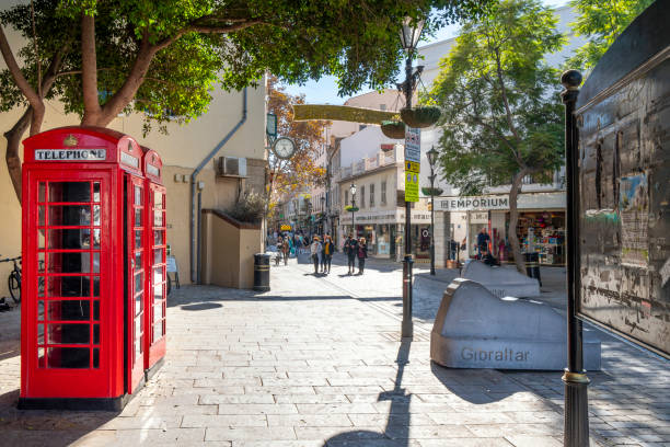 スペイン南部のイギリス領ジブラルタルのショップやカフェの旧市街のメインストリートエリアの入り口にある典型的な赤い英国の電話ボックス。 - pay phone telephone telephone booth red ストックフォトと画像