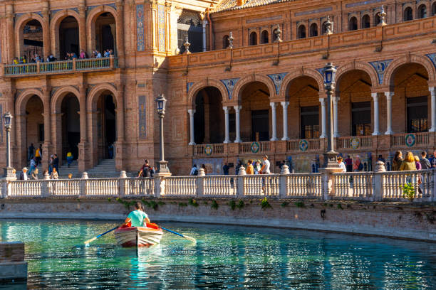 ein paar rudert ein kleines boot auf dem see auf einem sommertag auf der schönen plaza de españa in sevilla. andalusien, spanien. - plaza de espana seville spain parque maria luisa stock-fotos und bilder