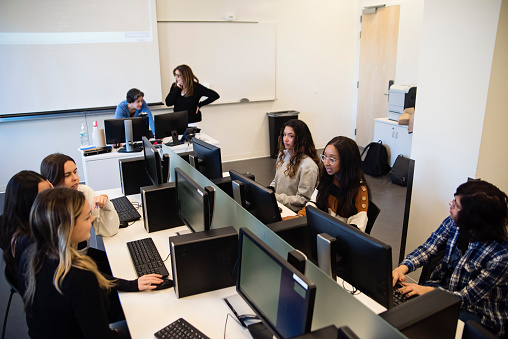 Smiling Hispanic STEM junior high school girl uses laptop at school.