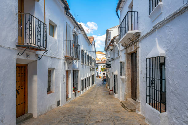 um longo beco estreito que leva à praça da cidade na vila branca espanhola de grazalema, espanha, na região andaluza do sul da espanha. - spain tower town square andalusia - fotografias e filmes do acervo