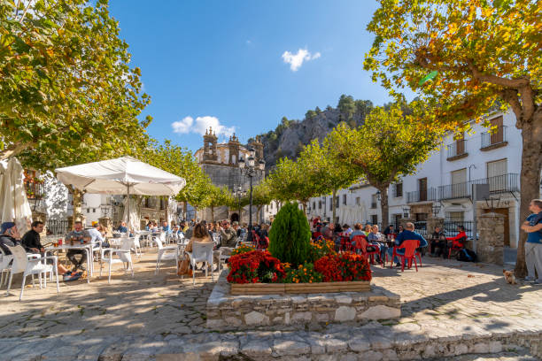 espanhóis e turistas locais desfrutam de cafés e lojas ao ar livre na praça central da cidade, plaza de españa, na vila caiada de branco de grazalema, na província de cádis, no sul da andaluzia, espanha. - spain tower town square andalusia - fotografias e filmes do acervo