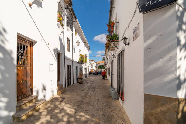 um longo beco estreito que leva à praça da cidade na vila branca espanhola de grazalema, espanha, na região andaluza do sul da espanha. - spain tower town square andalusia - fotografias e filmes do acervo