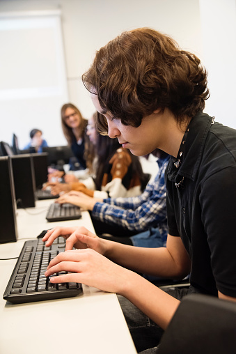 Gen Z teenage high school students using computer durning programming lesson, sitting in the computer laboratory.
