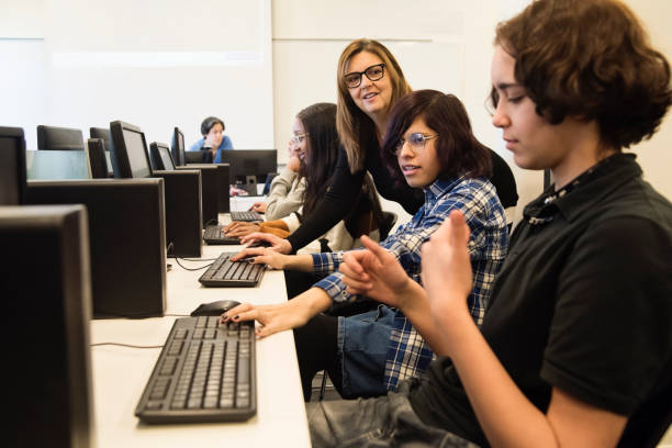 College students coding with teacher in tech lab classroom. College students coding with teacher in technology lab classroom. Students are a group of multi-racial and multi-gender persons. This is part of a series promoting diversity and equity in STEM. Horizontal waist up indoors shot with copy space. This was taken in Montreal, Quebec, Canada. nonbinary teacher stock pictures, royalty-free photos & images