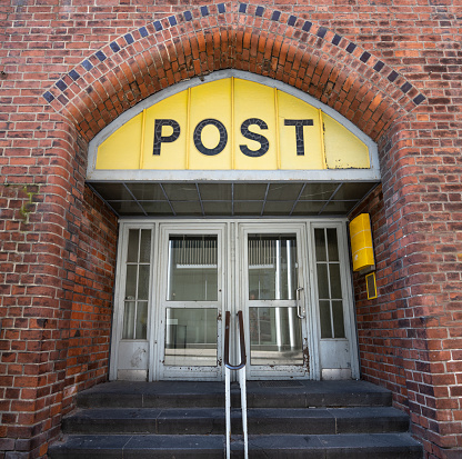 Entrance to the Post office in an historic building with a yellow sign, an old door and an arch of brick architecture in the old town of Lubeck, Germany,