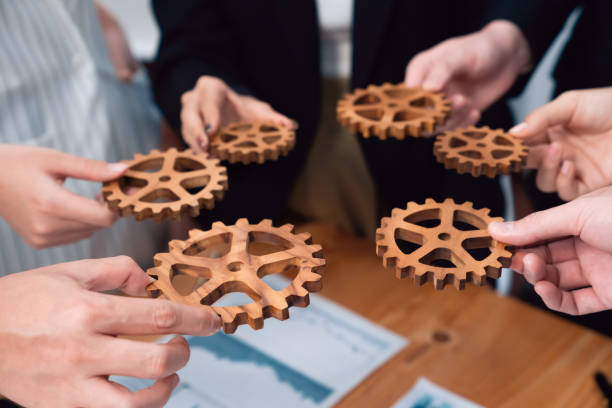 istock Closeup top view hands holding gears over table with BI reports for harmony. 1483949954