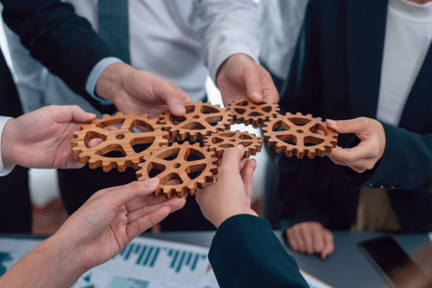 istock Closeup top view hands holding gears over table with BI reports for harmony. 1483952003