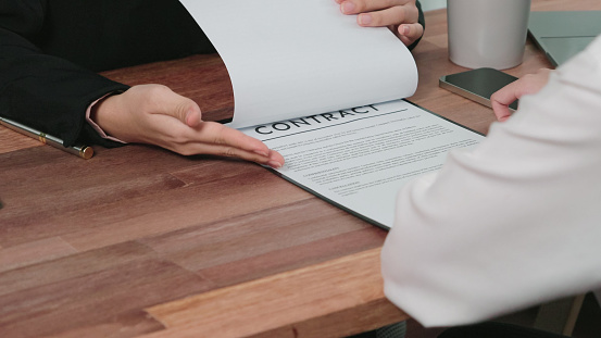 Close up of unrecognizable insurance agent showing his customer where to sign the contract.