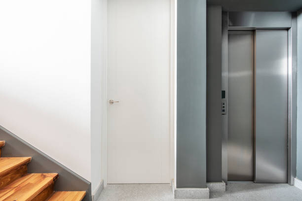 istock Front view of elevator with stainless steel doors and staircase with pine wood steps 1483958298