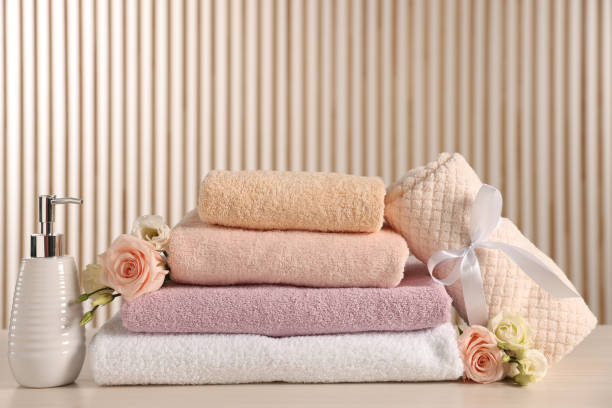 istock Soft towels, dispenser, roses and eustoma flowers on light wooden table 1483961881