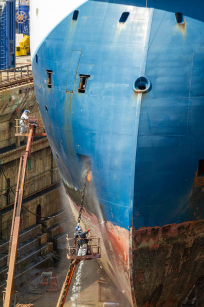 istock Workers cleaning impurities and removing paint with a pressure sandblasting from the hull of a merchant ship in a shipyard in Gibraltar 1483963104