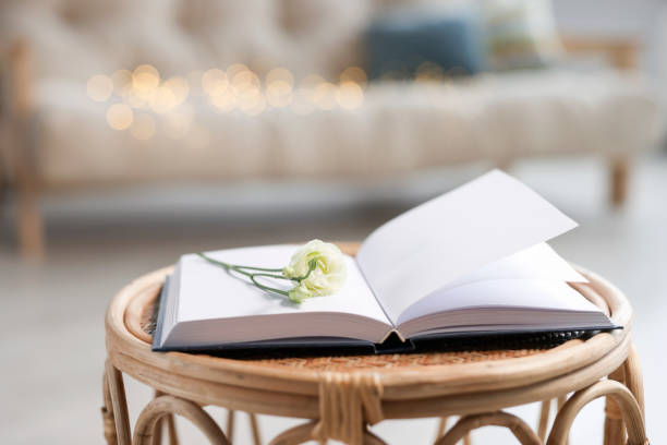 istock Open book and eustoma flower on rattan table in living room 1483963128