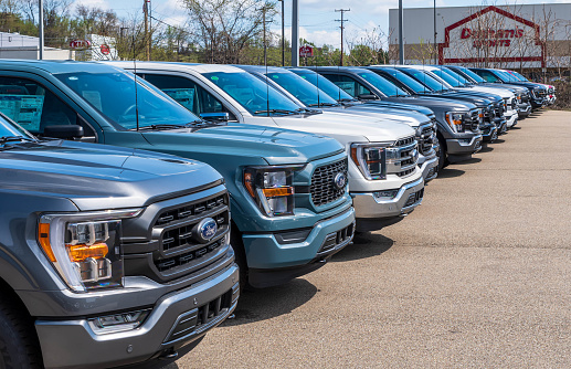 Monroeville, Pennsylvania, USA April 16, 2023 A line of new Ford F150 pickup trucks for sale at a dealership on a sunny spring day