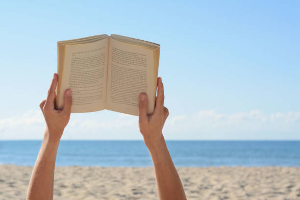 海の近くのビーチで本を読む女性、接写。テキスト用のスペース ストックフォト