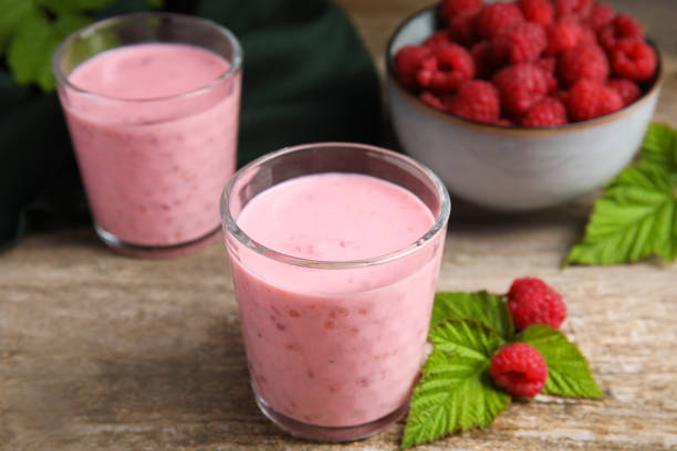 istock Tasty raspberry smoothie and fresh berries on wooden table 1483965333