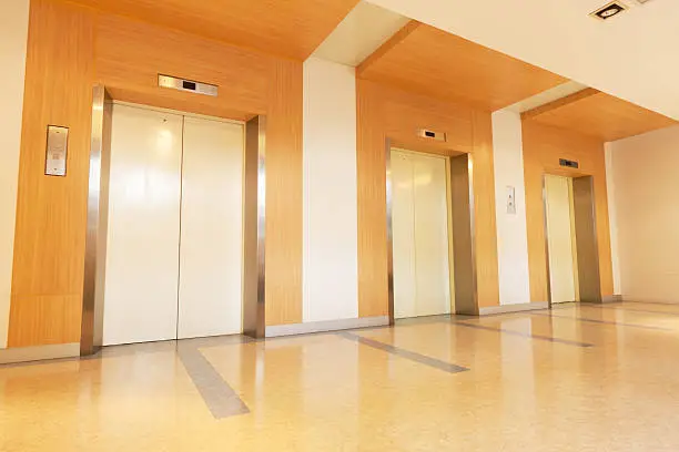 three elevators decorated with wood in office building