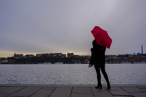 Woman with umbrella standing on promenade against sky